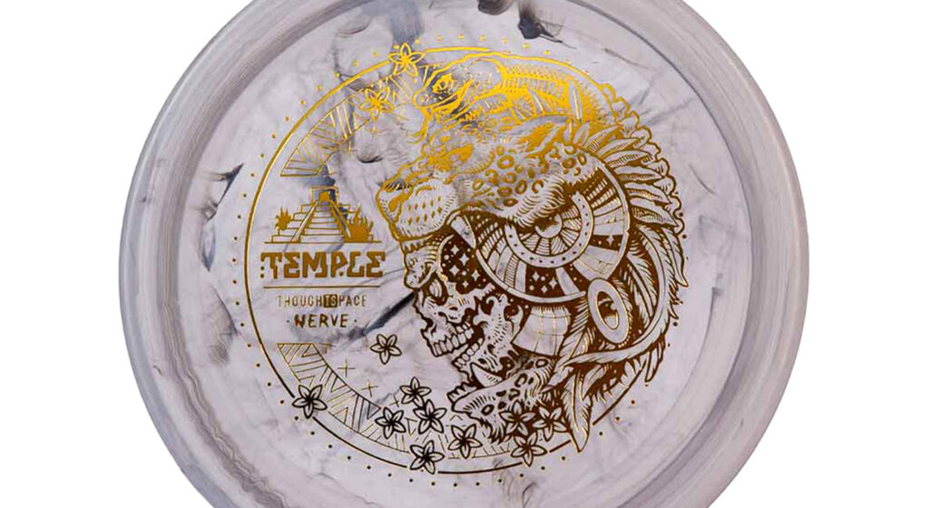 A Thought Space Athletics Test Blend Nerve Temple Grey Disc with Chrome Stamp.The image displayed on the disc showcases a skull adorned with a feather headdress, accompanied by a chameleon resting on top. The central design is encircled by an arrangement of flowers.